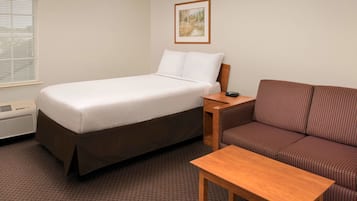 Una habitación de hotel con cama, sofá, una mesita y un cuadro en la pared.