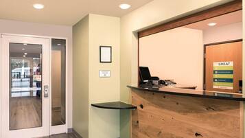 A reception desk with a computer, a phone, and a sign about the hotel's commitment to great service.
