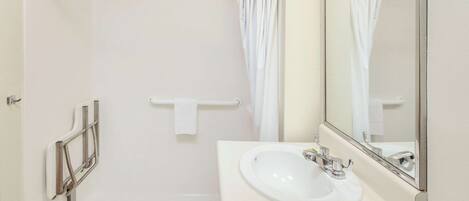 A bathroom with a white sink, a mirror, and a shower curtain.