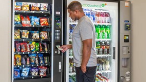 Ein Mann bedient einen Automaten mit Snacks und Getränken.