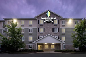 Un hotel de varios pisos con un cartel llamativo que dice 'Woodspring Suites'.