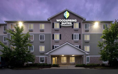 A multi-story hotel with a prominent sign reading "WOODS SPRING SUITES".