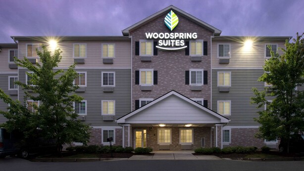 Ein mehrstöckiges Hotel mit einem gut sichtbaren Schild, auf dem "WOODS SPRING SUITES" steht.