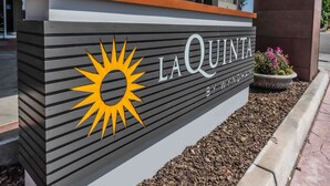 A sign for La Quinta by Wyndham with a sun logo. - La Quinta Inn & Suites by Wyndham Fowler (Fowler)