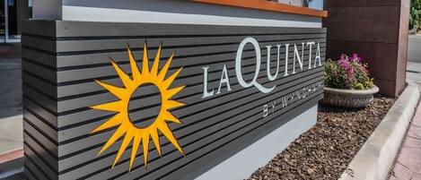 Un letrero de La Quinta by Wyndham con un logo de sol.