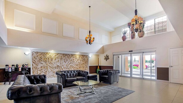 A spacious lobby with a high ceiling, leather sofas, a glass coffee table, and a chandelier. - La Quinta Inn & Suites by Wyndham Fowler (Fowler)