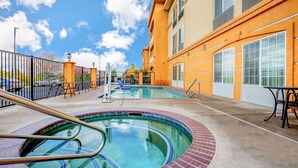A swimming pool area with a brick border, a metal ladder, and a table with chairs. - La Quinta Inn & Suites by Wyndham Fowler (Fowler)