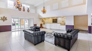 A spacious lobby with leather sofas, a chandelier, and a large window overlooking the street. - La Quinta Inn & Suites by Wyndham Fowler (Fowler)