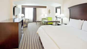 Une chambre d’hôtel avec un grand lit, un bureau, une chaise, un canapé et un téléviseur.