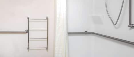 Un baño con ducha, perchero y barra de apoyo.
