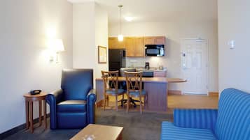 Een ruimtelijke woonruimte met kitchenette, een eethoek met stoelen, een bank en een kleine tafel.