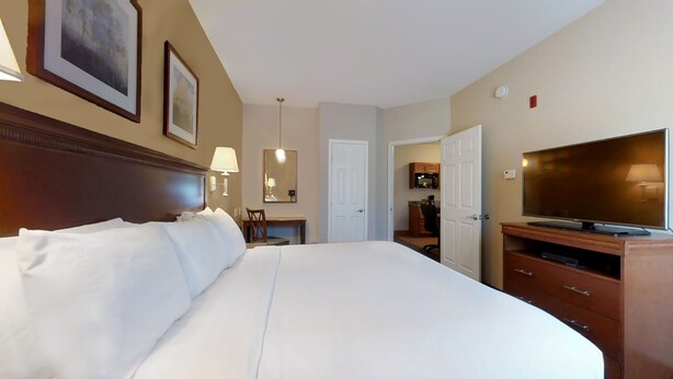Hotelkamer met een groot bed, een televisie, een bureau met stoel en een deur naar de badkamer.