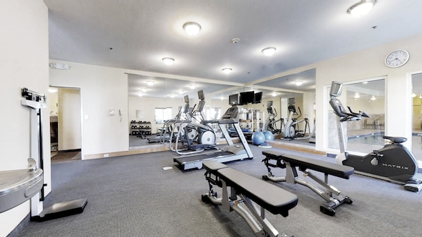 A gym with treadmills, elliptical machines, and a bench.