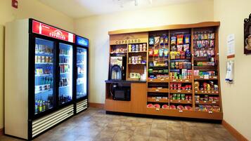 Un área de venta con un refrigerador y una estantería repleta de refrigerios y bebidas.