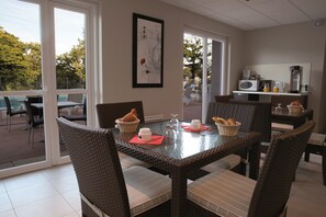 Enjoy meals in this cozy dining area with a glass table and wicker chairs, surrounded by a beautiful view.