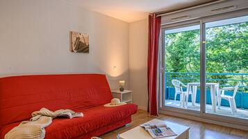 A red sofa, a white table, and a balcony with blue chairs.