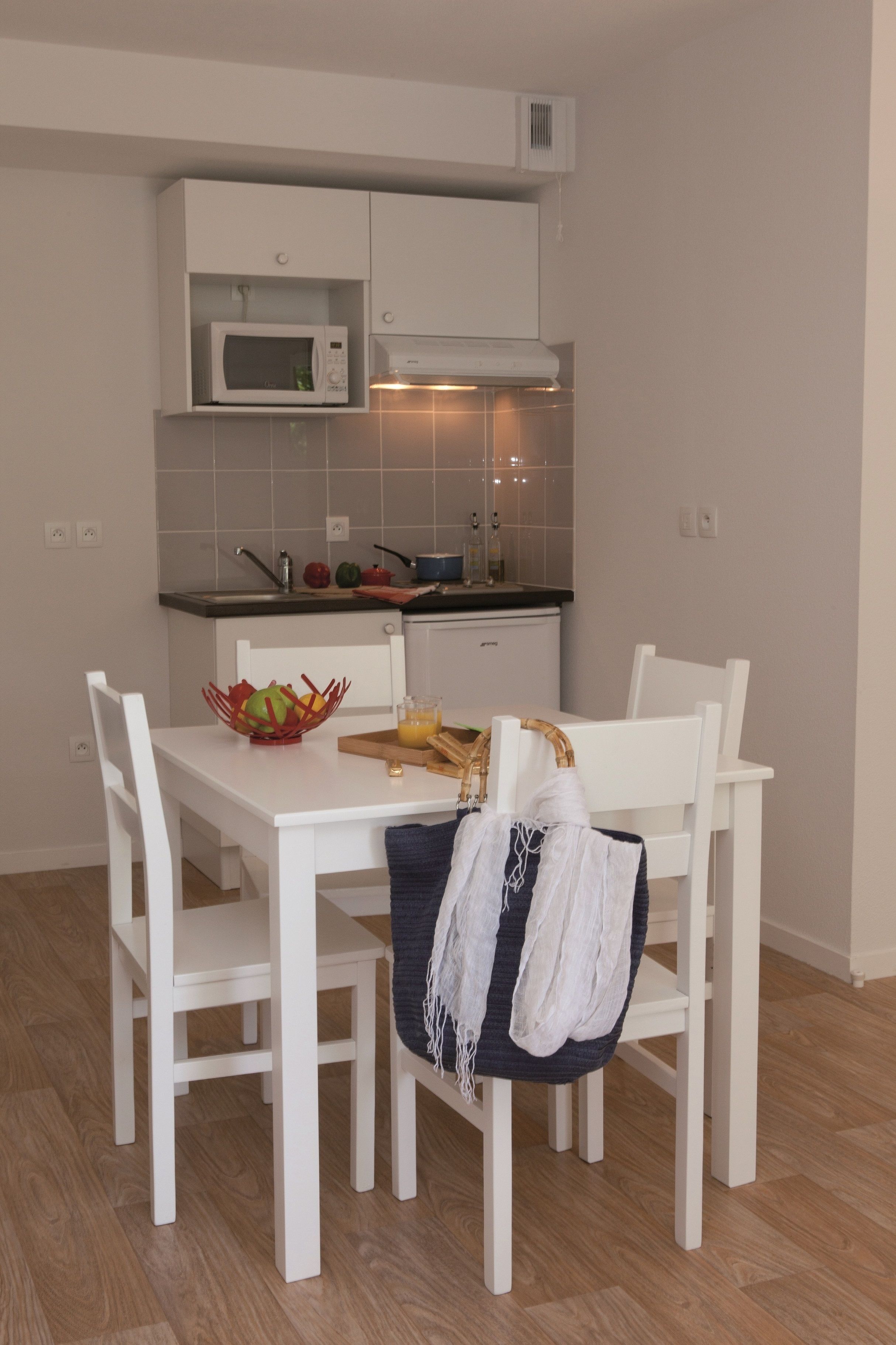 Una cocina moderna con armarios blancos, un microondas y una mesa de comedor con sillas.
