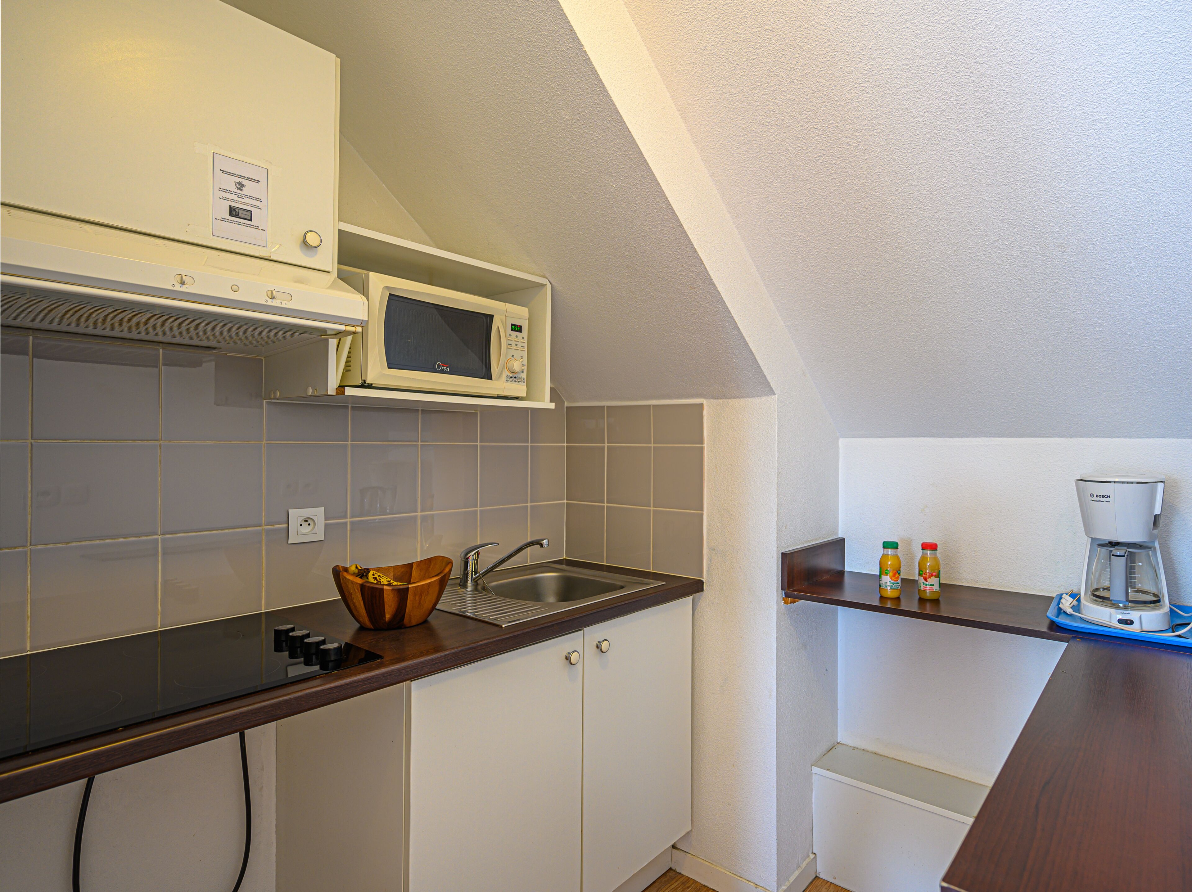 A kitchen with a microwave, sink, and coffee maker.
