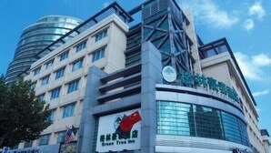 A hotel with a modern design, featuring a prominent curved glass facade and a green tree logo. - GreenTree Inn Suzhou Changshu South HaiYu Road Hotel (Suzhou)
