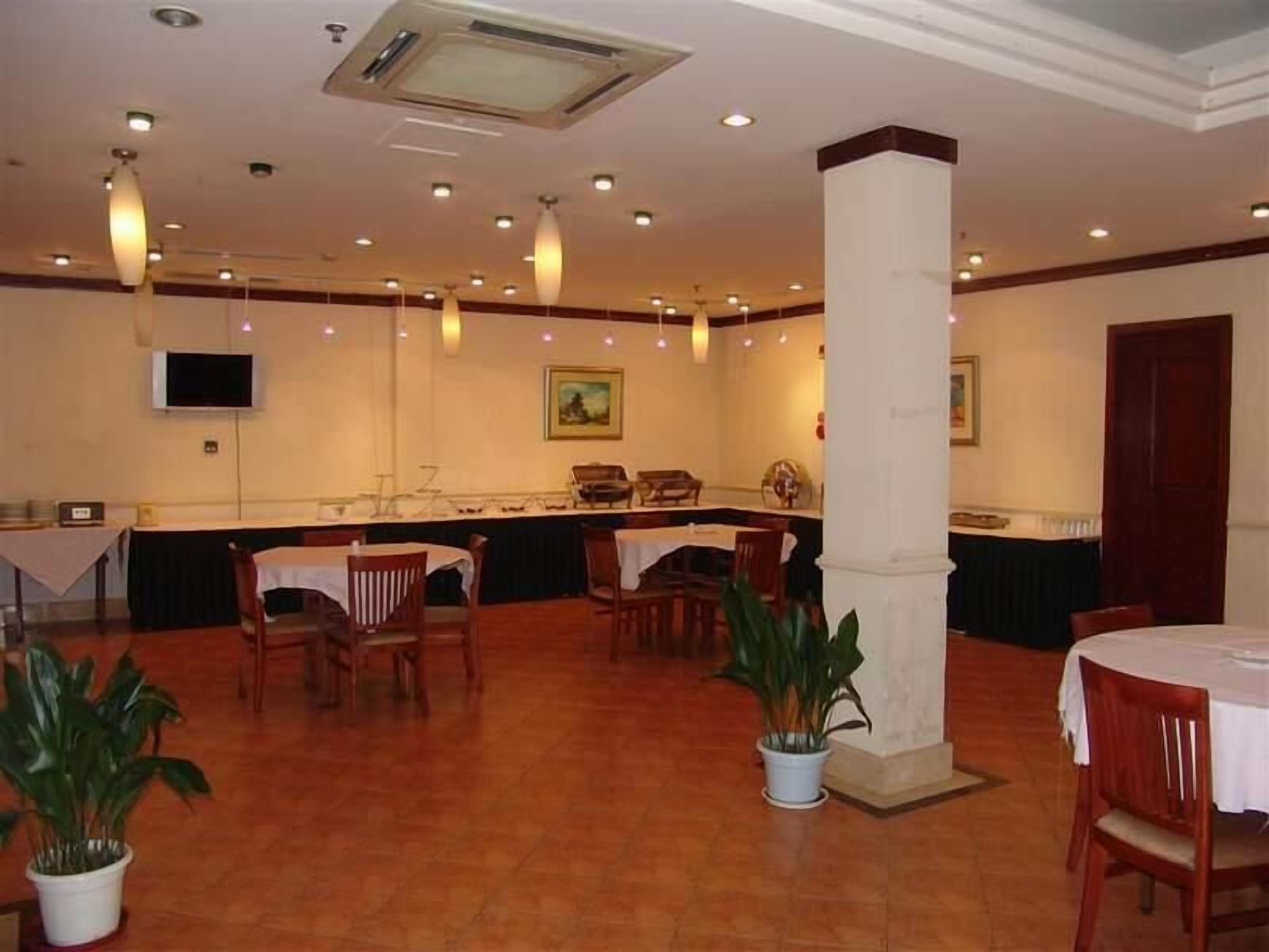 A spacious room with multiple tables and chairs, a large pillar, and a television mounted on the wall.