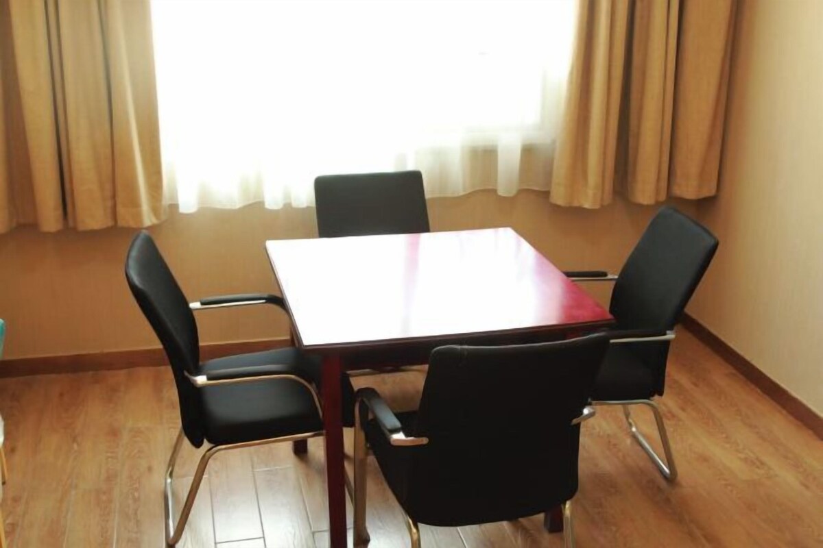 A room with a wooden floor, a red table, and four black chairs.