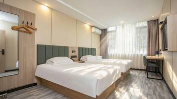 Une chambre d’hôtel avec deux lits, un bureau, un miroir et une armoire.