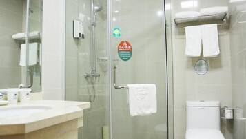 Un baño con cabina de ducha de vidrio, inodoro blanco y lavamanos con espejo.
