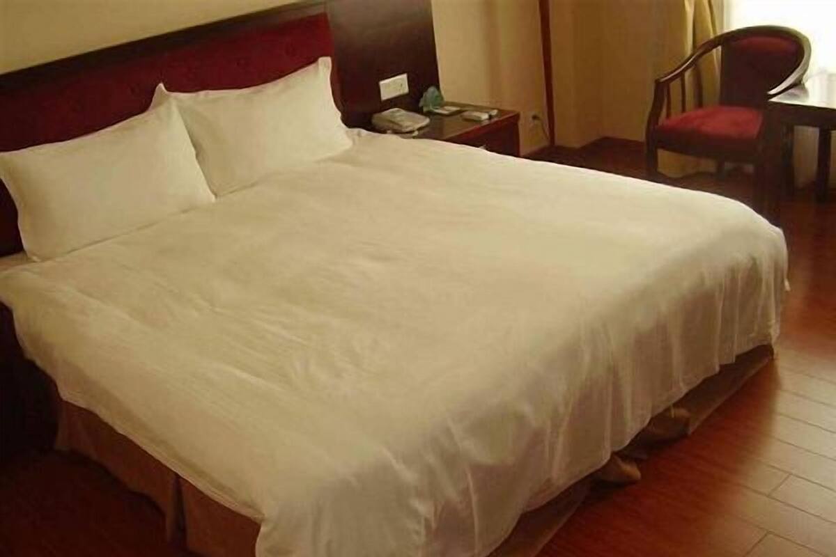 Una cama bien tendida con sábanas blancas en una habitación de hotel.