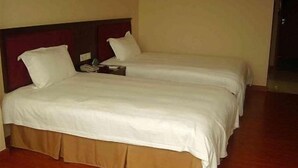 Habitació d'hotel amb dos llits individuals, sòl de fusta i un disseny senzill i net.