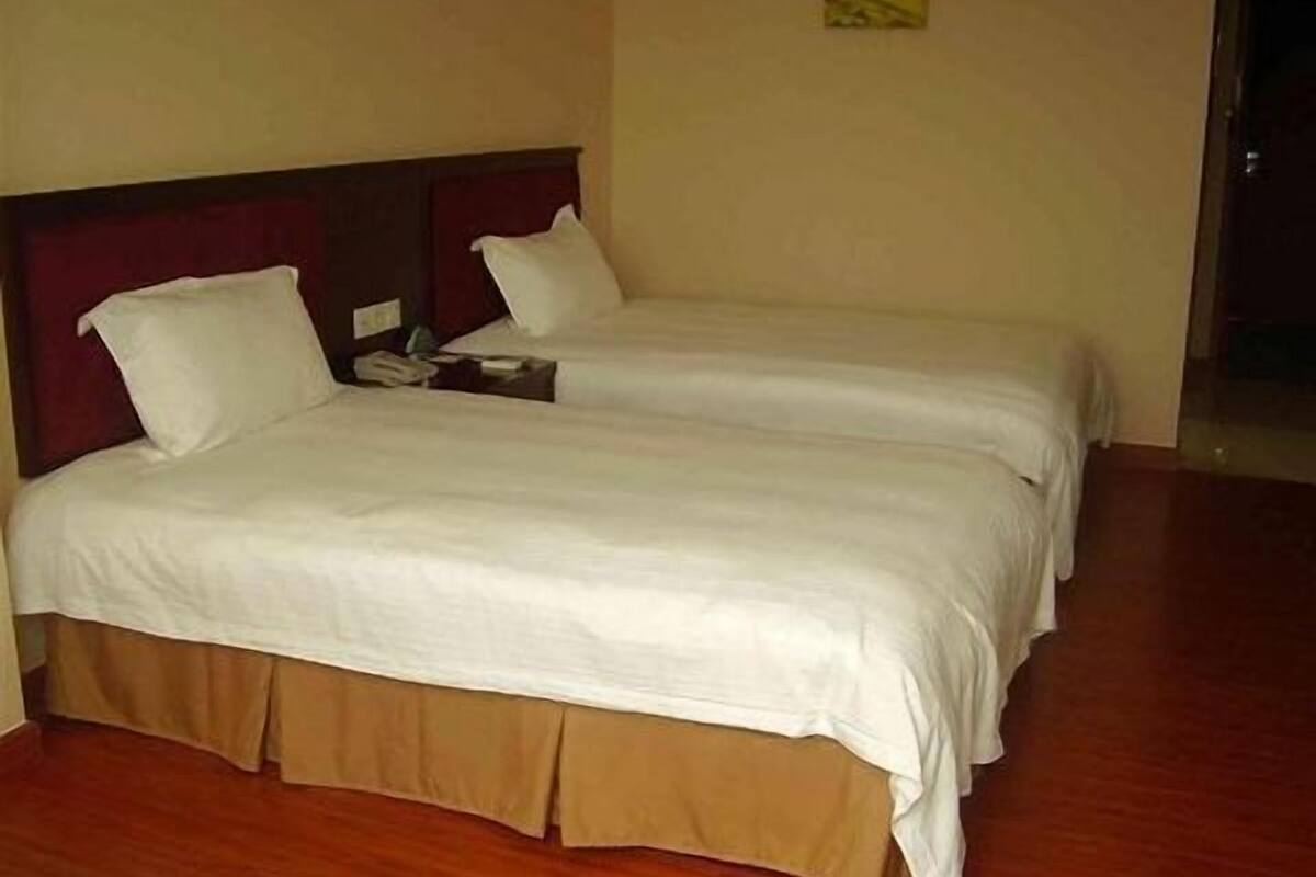 Habitación de hotel con dos camas individuales, suelo de madera y un diseño sencillo y limpio.