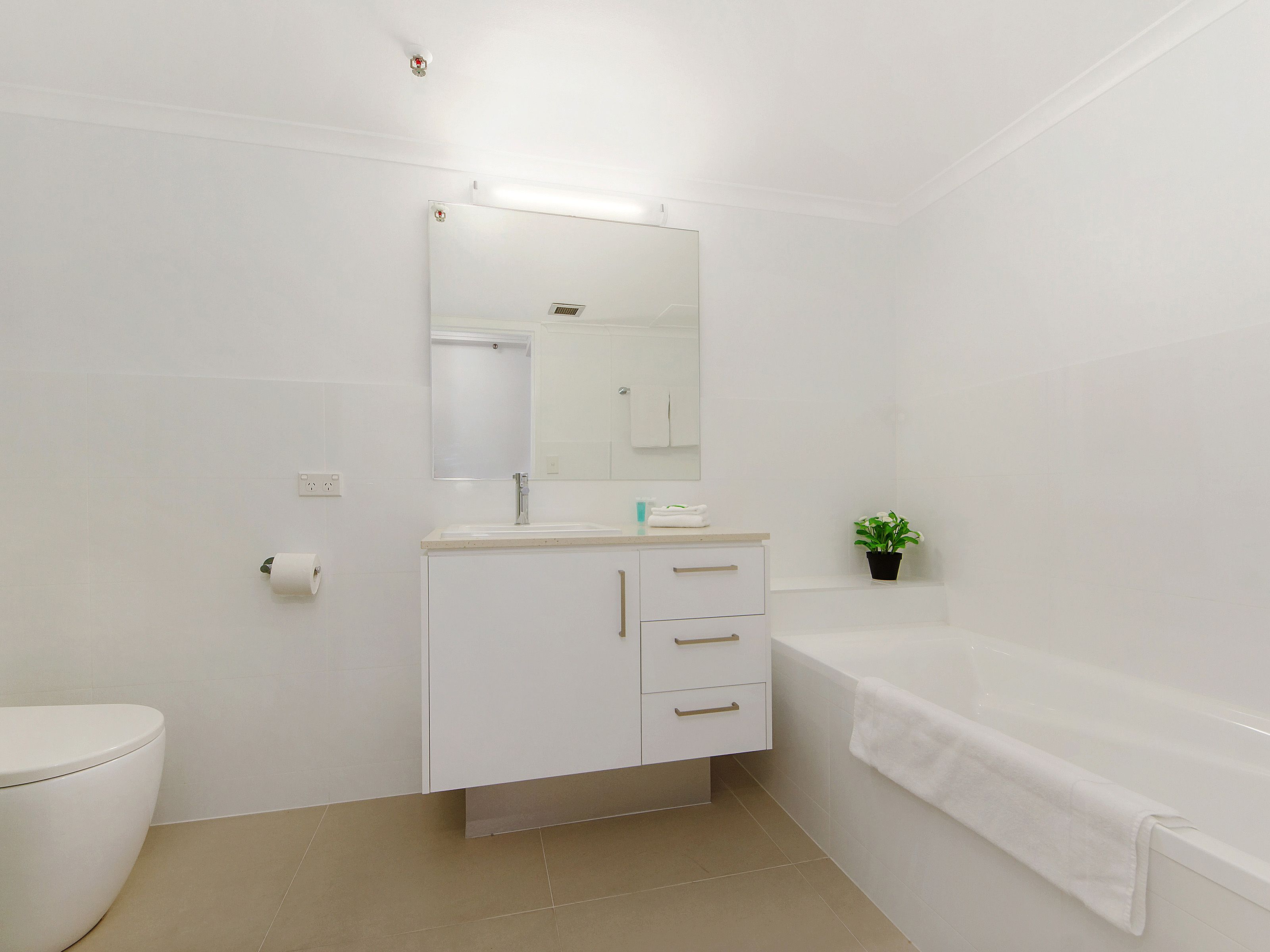 Un baño moderno con inodoro, lavamanos, espejo y bañera.