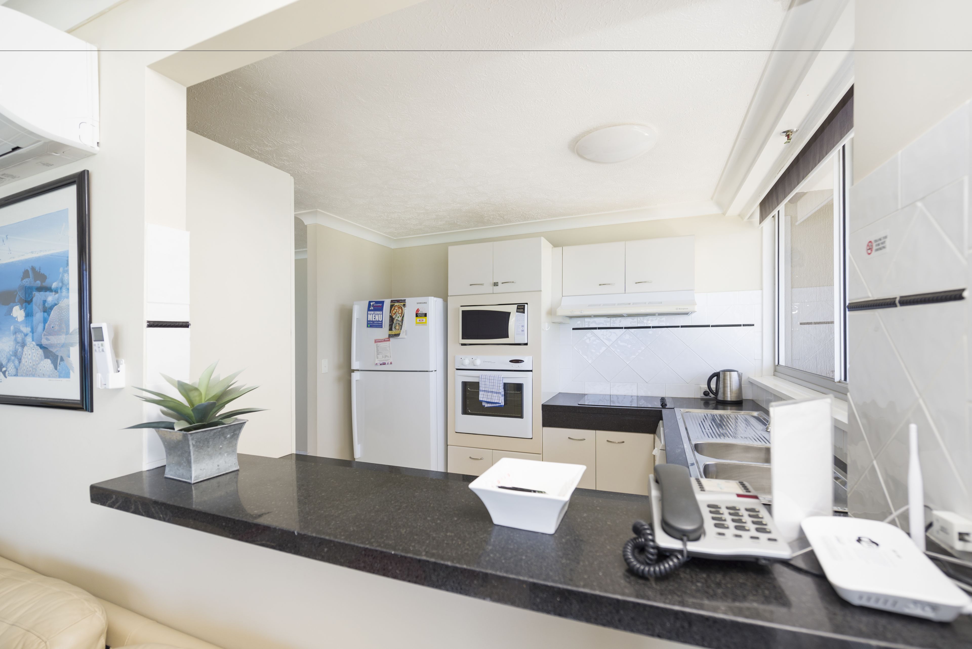 A modern kitchen with white cabinets, a black countertop, and a built-in oven.