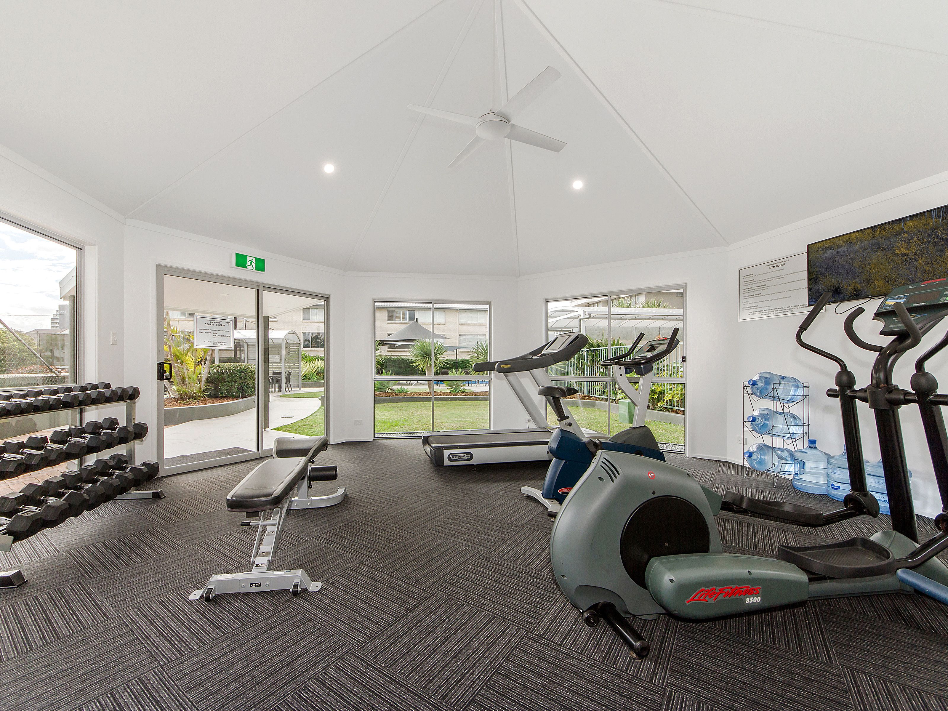 A gym with treadmills, dumbbells, and a weight bench.