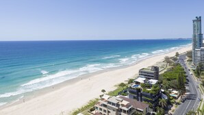 A coastal hotel with a beach view, modern architecture, and a road running parallel to the beach. - Sunbird Beach Resort (Main Beach)