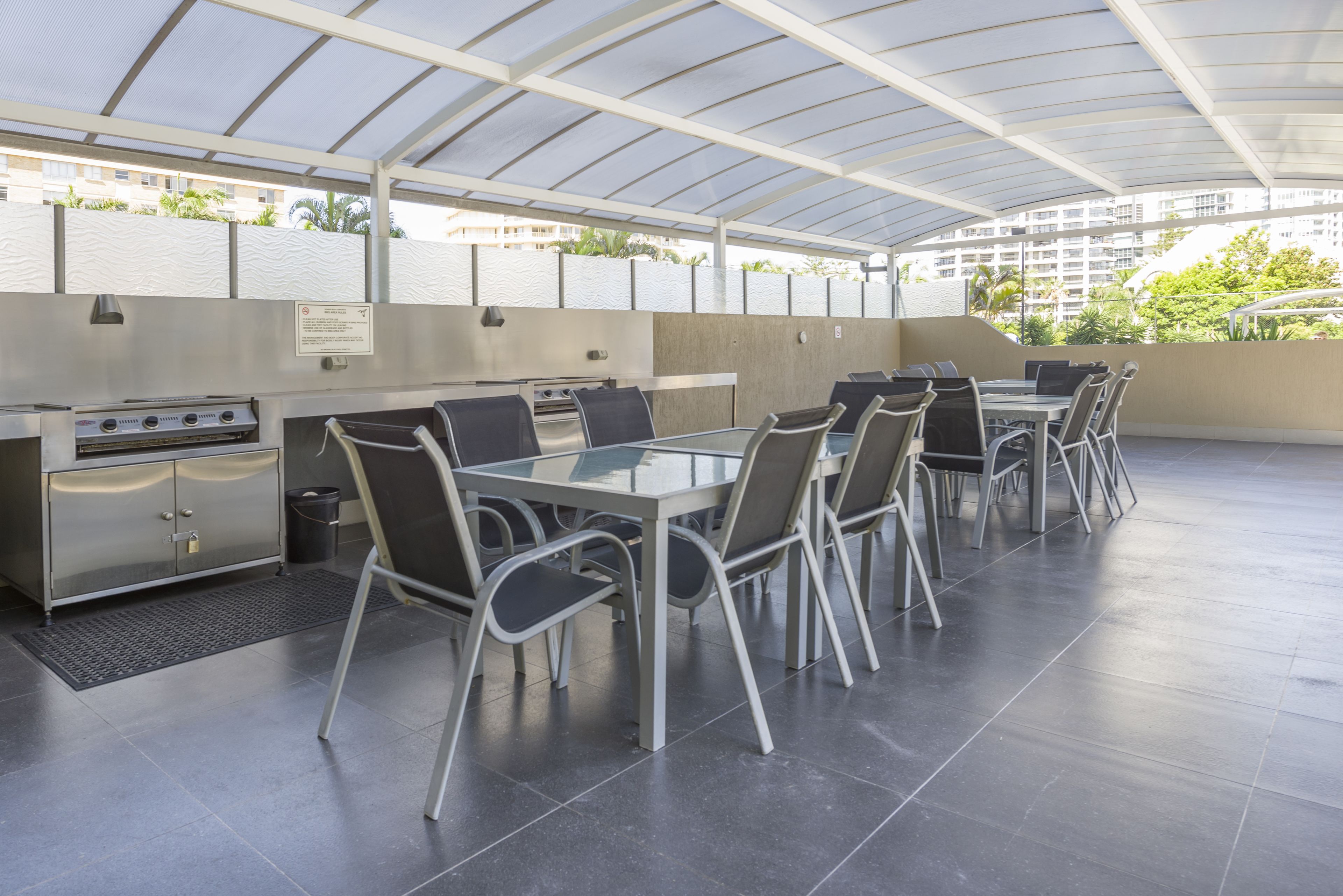 An outdoor patio with a covered seating area, a grill station, and a view of the surrounding buildings.