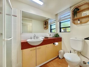A bathroom with a white sink, beige cabinets, a mirror, a toilet, and a window with blinds. - Mermaid Beach Park View Resort (Mermaid Beach)