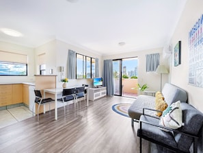 A modern, well-lit living room with a dining area, a balcony with a city view, and a kitchen with a view. - Mermaid Beach Park View Resort (Mermaid Beach)