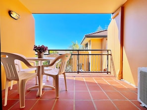 A balcony with a table and chairs, a potted plant, and a view of a building in the background. - Mermaid Beach Park View Resort (Mermaid Beach)