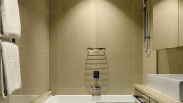 Une salle de bain moderne équipée d’une baignoire, de toilettes et d’une douche à parois de verre.