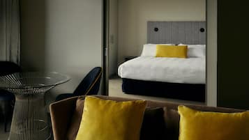 Quarto de hotel com uma cama, uma mesa de vidro e uma cadeira.