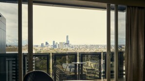 A balcony with a glass partition, offering a city view. - The Kinson (Melbourne)