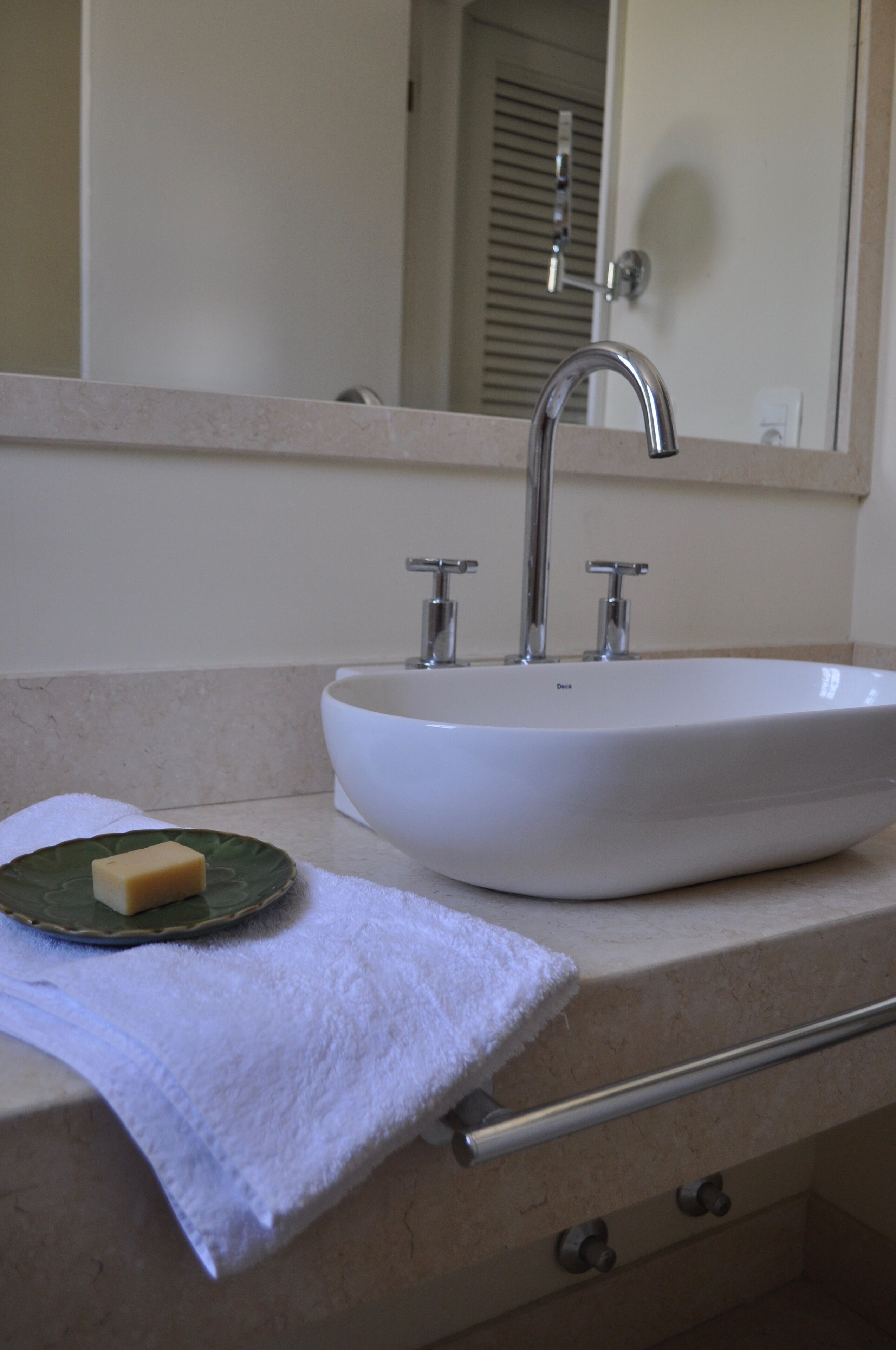 A bathroom sink with a mirror above it, a towel, and a soap dish.