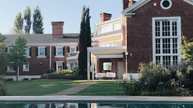 Una piscina con el reflejo claro de un edificio y árboles.