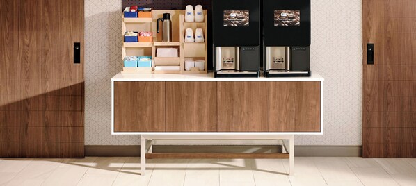 A modern kitchen with a wooden countertop, coffee machines, and storage cabinets.