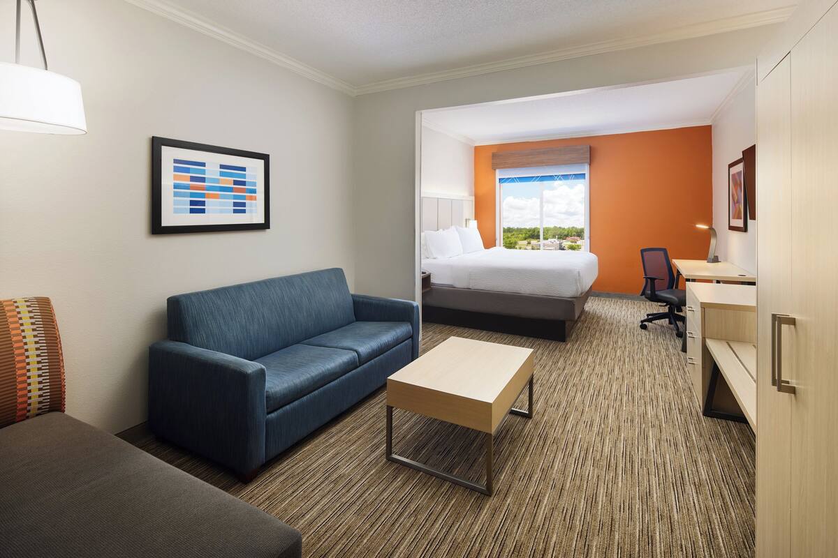 A hotel room with a bed, a desk, a sofa, and a small table.