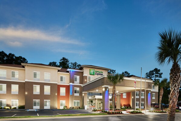 Un hotel de varios pisos con un llamativo letrero de 'Holiday Inn Express', una entrada techada y un estacionamiento.