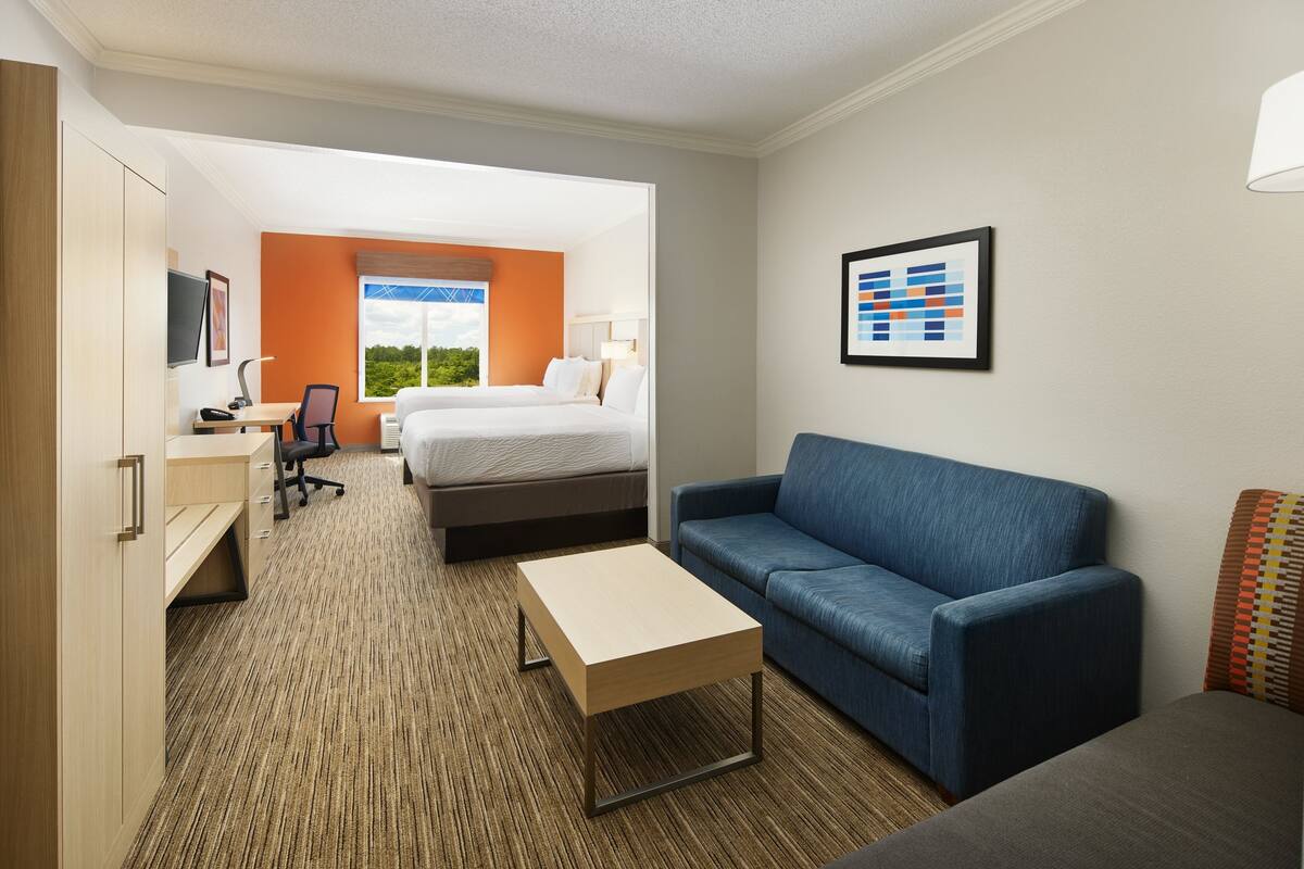 A hotel room with a bed, a desk, a chair, a sofa, and a framed picture on the wall.