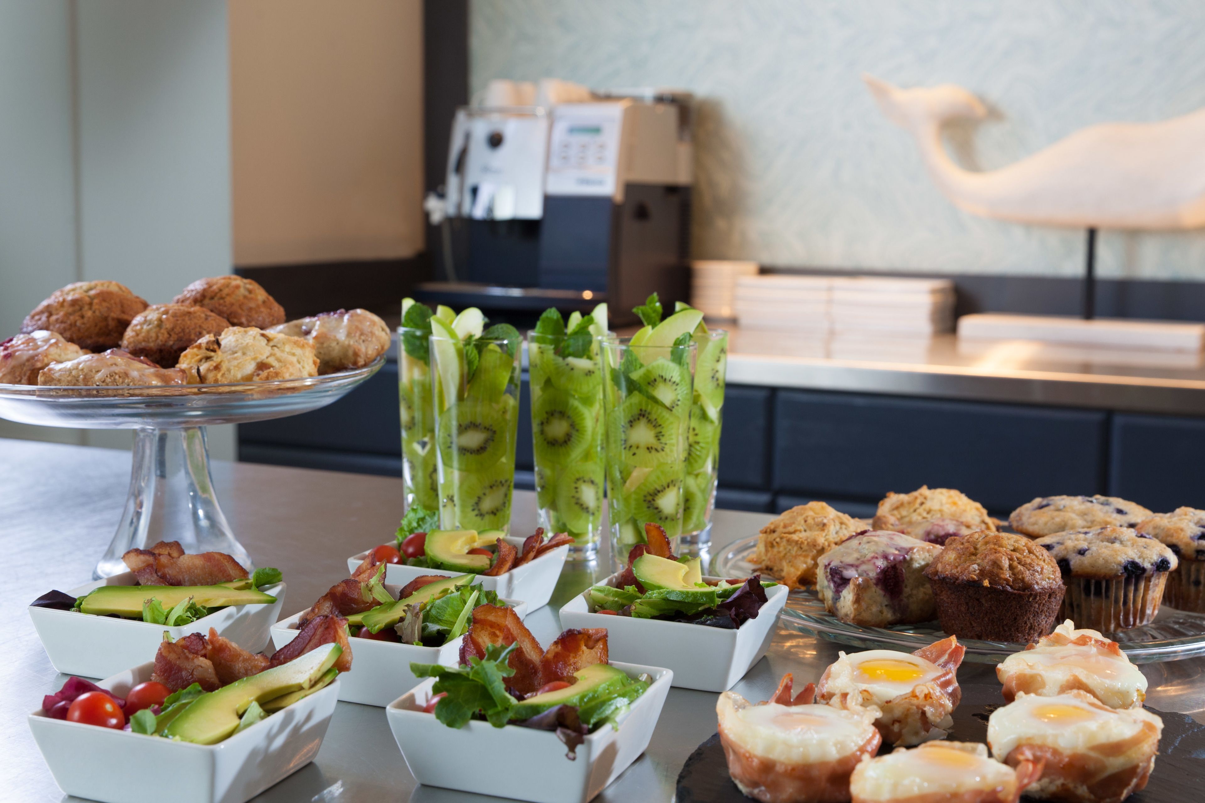 A buffet with various food items including salads, muffins, and beverages.