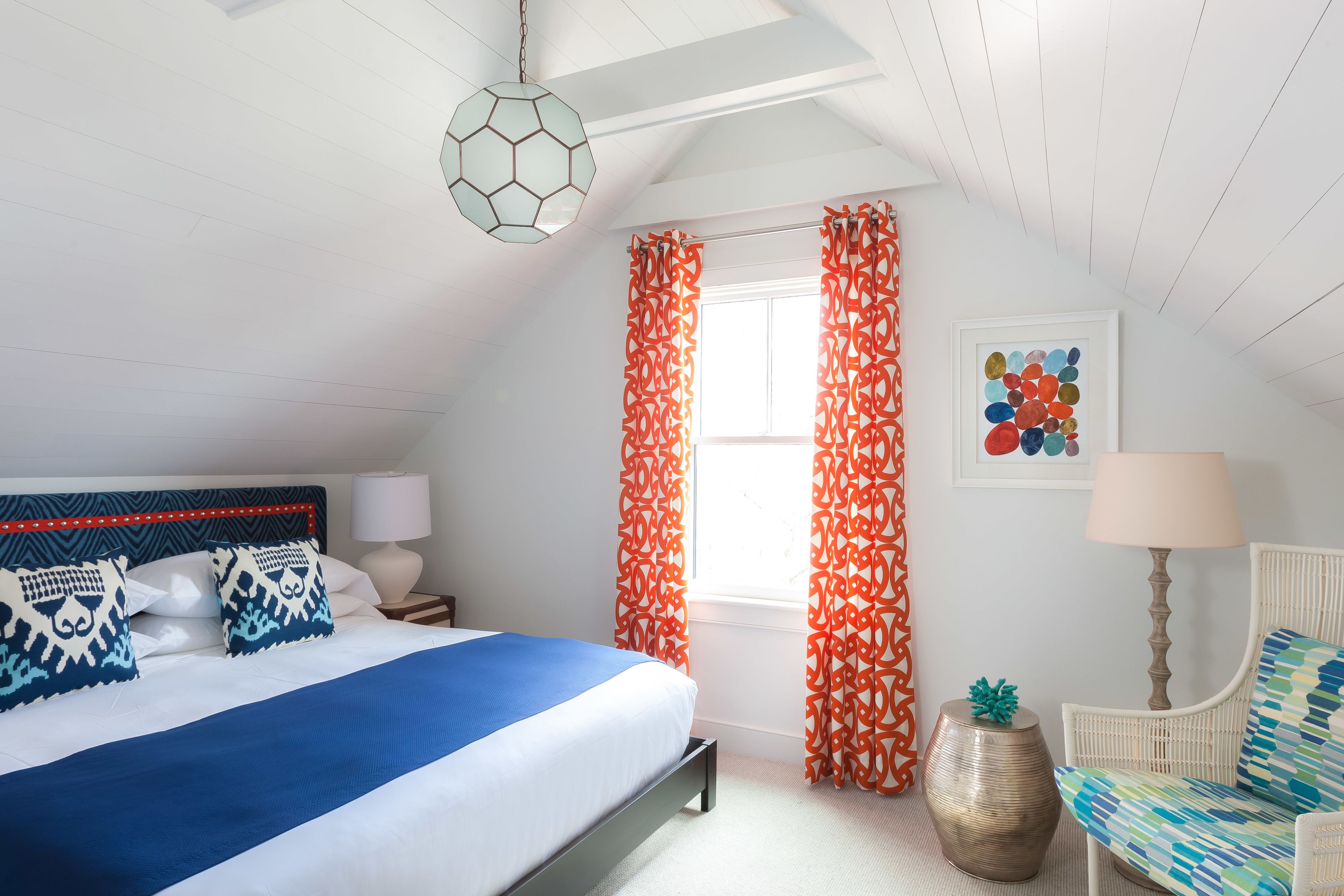 A bedroom with a bed, a chair, a lamp, a decorative globe, and curtains.