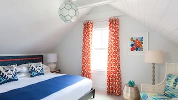 A bedroom with a bed, a chair, a lamp, a decorative globe, and curtains.